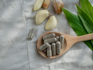 Organic medical pills with herbal plant on cloth background. Natural medicine concept