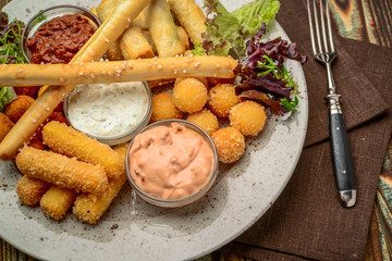 Allsorts of fried snacks with two different sauces on black background