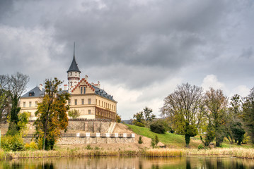 Gorgeous castle in red color in autumn colors with lake beside