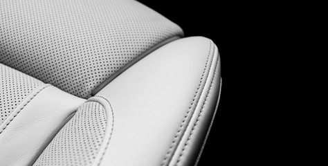 White leather interior of the luxury modern car. Perforated white leather comfortable seats with stitching isolated on black background. Modern car interior details. Car detailing. Car inside