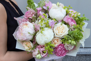 White pink big expensive bouquet with peonies, carnation and roses in woman hands