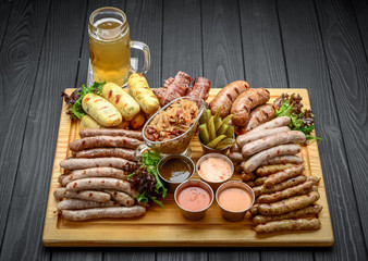 Grilled sausages with glass of beer on a wooden table