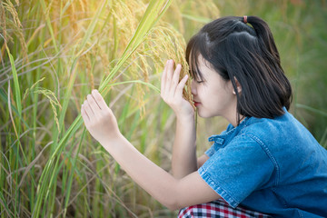 Asian girl farmer holding rice plant on yellow rice field