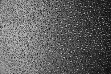 abstract background: a lot of drops on a dark surface. Center in sharpness, blurred edges. Black and white photo