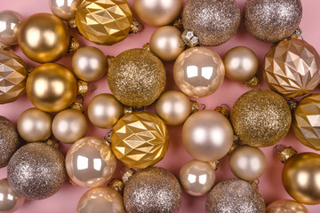 Festive pink background with gold and silver Christmas balls. Flat lay, top view.