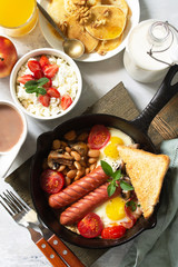 Keto breakfast: fried eggs, sausages, beans, bacon, mushrooms, grilled toasts, orange juice, cottage cheese, pancakes and cocoa on a light stone table. Top view flat lay background.