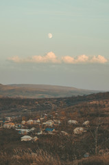 The moon overlooking a rural fall atmosphere with a smoky background in a small village through sunset clouds
