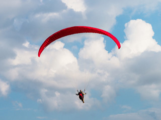 Paraglider is flying in the blue sky.