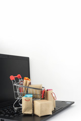 Shopping cart with purchases - packages and boxes on the modern laptop. Online shopping, black...