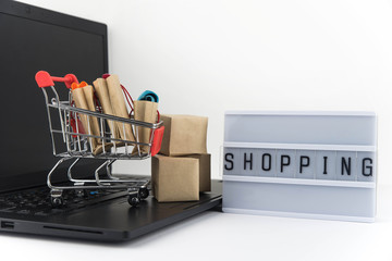 Shopping cart with purchases - packages and boxes on the modern laptop. Online shopping, black friday and sale concept.