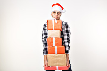 Holidays and presents concept - Funny man in Christmas hat holding many gift boxes on white background with copy space
