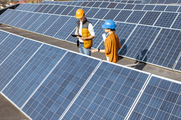 Two engineers or architects examining the construction of a solar power plant, standing with...