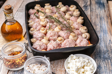 Delicious homemade food. Turkey meat mince balls with champignons, carrots, spices and herbs in a cast iron baking dish. Horizontal shot. Close-up