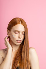Fototapeta premium Beautiful young ginger woman with cream on face