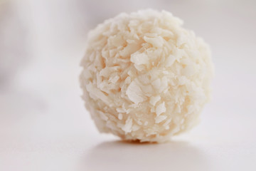 White chocolate candies with coconut filling on a white background. High key photo.