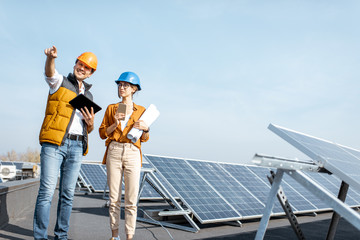 Two engineers or architects examining the construction of a solar power plant, walking with digital...
