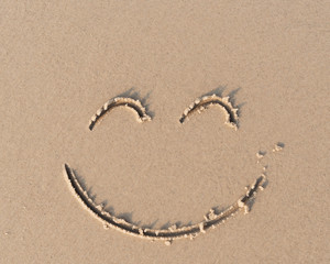 Smile symbol on sand beach.