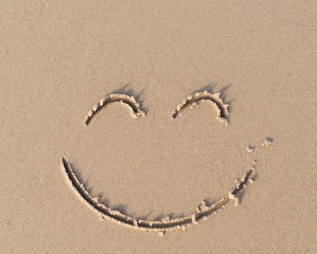 Smile symbol on sand beach.