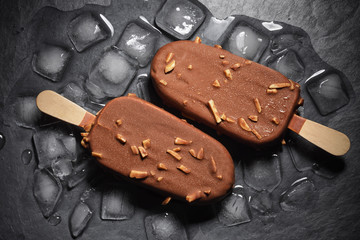 Chocolate ice cream popsicle on black background with ice
