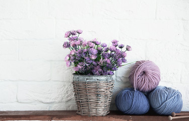 balls of cotton thread and a shabby old pot on a shelf, artificial flowers, decor elements.