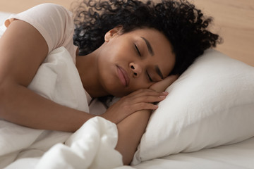Obraz na płótnie Canvas Peaceful African American woman sleeping on soft pillow close up