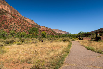 Landscape of walking path, greenery and multi-colored stone hillside near Jemez Springs in New Mexico