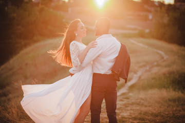 mixed couple of people hugging on sunset background