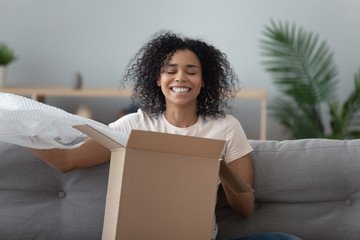 Smiling satisfied African American woman client unboxing parcel