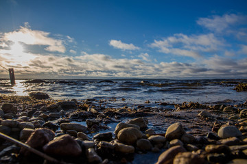 Ice and snow on beach coast with shadows in cold winter evening sunset sky orange sun light