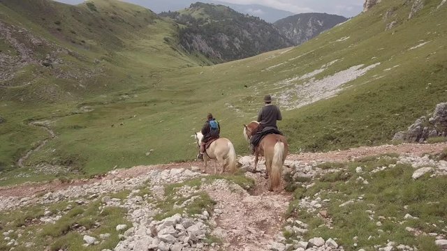Aerial follow of two guys riding through alpine area in the Dolomites in Italy.