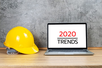 Yellow safety helmet and laptop computer with 2020 TRENDS text on white screen
