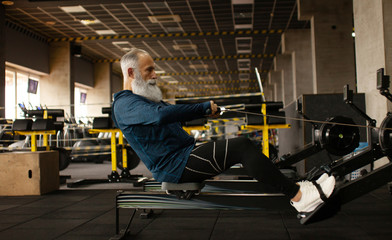 Fototapeta na wymiar Serious mature male is having intense workout in gym.