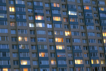 Block of grey concrete flats with some windows light on