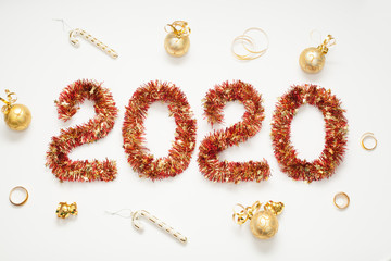 The figure 2020 is made of a red garland decorated with a Santa hat and gold toys and candies. isolated on white background. The concept of a New year.