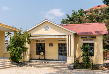 Fototapeta na wymiar Nha Trang, Vietnam - March 11, 2019: Chua Loc Tho Buddhist temple, primary school and orphanage. Care-to-Help project sponsored yellow school building under blue sky with green foliage.