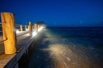 Illuminated Footbridge from beach into Carribean Sea by night