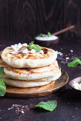 Onion, mint and cheese small flatbreads served on a wooden plate. Gozleme - crispy, golden Turkish flatbreads.