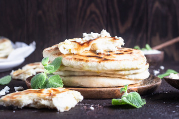 Onion, mint and cheese small flatbreads served on a wooden plate. Gozleme - crispy, golden Turkish flatbreads.
