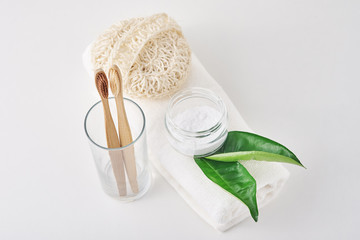 Wooden bamboo toothbrushes in glass, baking soda and towel on a white background. Personal hygiene concept