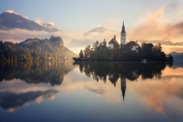 Fototapeta na wymiar Stunning sunrise on Bled lake in Slovenia with the Pilgrimage Church of the Assumption of Maria and Bled Castle in the background