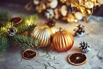 Christmas decorations with golden balls, fir tree branch and garland lights on a dark background