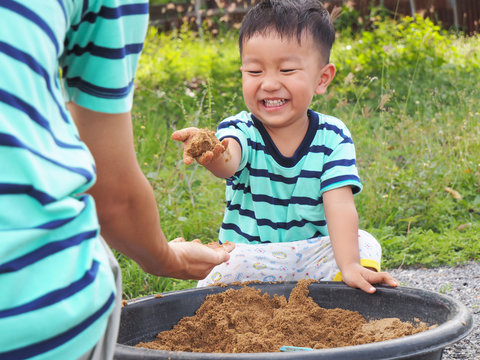 Asian cute kid laughing with happy smiling face,while playing sand with dad,funny concept,happy family time.