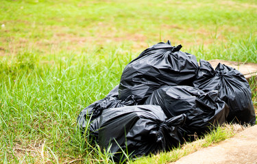Black Trash bags on the ground.Pile of black garbage on the footpath at side road.