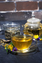 cup of tea with aromatic herbs on a dark background, vertical
