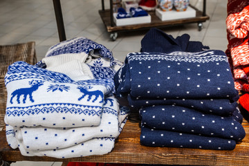 Christmas sale in the Mall. Winter sweaters with traditional ornament: deer. Selective focus.