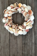 Scallop seashell wreath on rustic wood background with copy space.