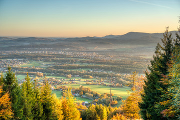 Fototapeta premium view of a valley full of industry that smokes and house from the mountain at sunrise in autumn