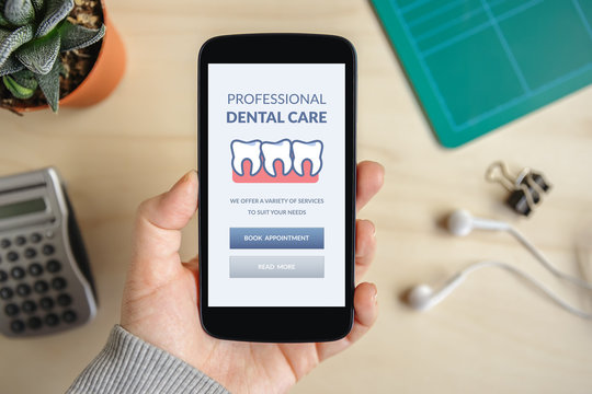 Hand holding smart phone with dental care concept on screen. Top view