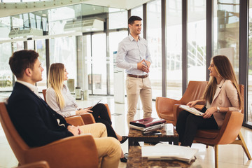 Business team working on new project and smiling. Man and women sitting together in modern office for project discussion.