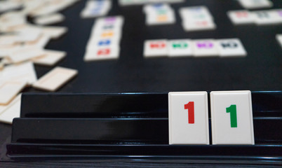 Friends playing to a strategy game board on a table. Blocks of number and statistic for score and win in a tabletop at home. Hands adding Plastic pieces on a competition.